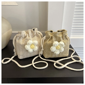 Detail of woven straw bucket bags with knitted sunflower accents and drawstring