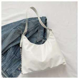 Detail of white half-moon shoulder bag with silver chain and wide strap on denim