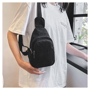 Detail view of the black corduroy chest bag featuring a dual zipper and adjustable strap