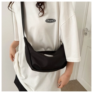 Detail of black half-moon canvas crossbody bag featuring fashion label and wide strap