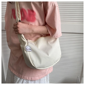 Detail of off-white canvas crossbody bag with cute sheep charm and adjustable strap