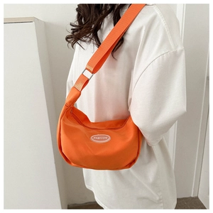 Close-up of bright orange canvas sling bag with adjustable strap and Fashion logo