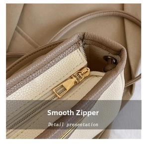 Close-up of smooth golden metal zipper on two-tone lychee pattern leather tote bag
