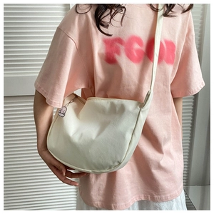 Detail view of a beige nylon crescent crossbody bag with a cute pink cartoon keychain