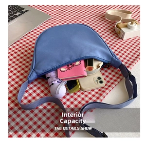 Detail showing high-capacity interior of blue nylon crossbody bag with daily essentials