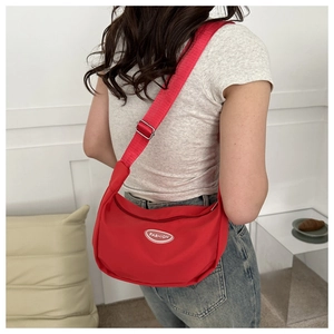 Close-up of red nylon dumpling bag with fashion rubber label and wide shoulder strap