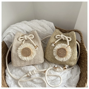 Close-up of woven straw bucket bags with sunflower accents and cotton drawstring straps