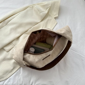 Quilted beige tote bag with large capacity showing interior storage on white linen