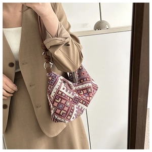 Detailed shot of retro ethnic woven dumpling bag with brown leather strap and metal buckle
