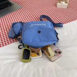 Light blue nylon crossbody bag with mini pouch showing phone and makeup storage