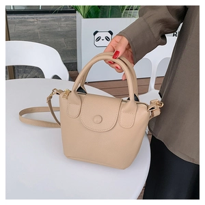 Detail of beige bucket bag showing pebbled leather texture and elegant top handle