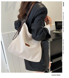 Fashionable creamy white large tote bag with brown straps worn on shoulder by a model