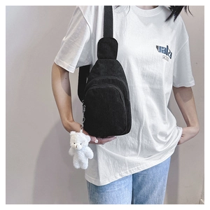 Detail of black corduroy chest bag with cute plush bear pendant and adjustable strap