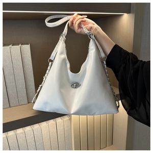 Detail of silver Saturn logo and metallic chain on white crescent hobo shoulder bag