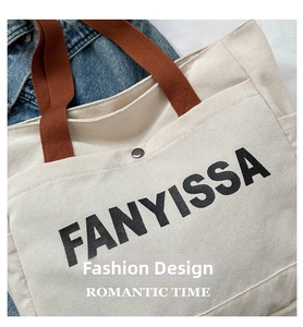 Detail of canvas tote bag showing metal magnetic buckle closure and FANYISSA text
