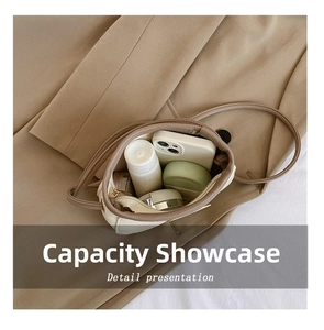 Interior storage view of cream pebbled leather crossbody bag showing phone and cosmetics