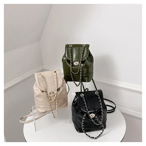 Three bucket backpacks in beige, green, and black with metal chain straps and gold locks