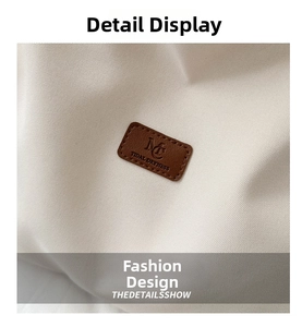 Macro detail of canvas texture with a stitched brown leather logo tag and embossed lettering