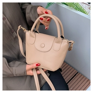 Dettaglio della borsa a secchiello beige con trama a grana e finiture metalliche dorate