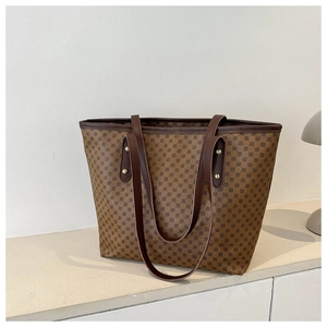 Detail of vintage monogram tote bag featuring leather straps and gold rivet accents