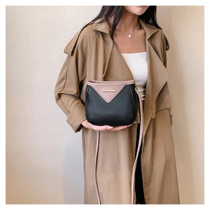 Detail view of contrast color bucket bag with litchi texture on model overcoat