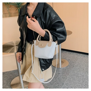 Dettaglio di una mini borsa a secchiello in finta pelle bianca e beige con tracolla