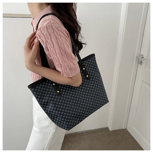 Side view of model wearing a large tote bag with blue geometric pattern and leather handles
