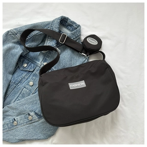 Détail du sac bandoulière en nylon noir avec étiquette fashion et petite pochette ronde