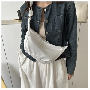 Close-up of white crescent canvas crossbody bag featuring the oval Fashion emblem detail