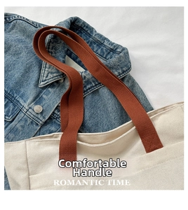 Detail of cream canvas tote bag with brown woven handles on denim background