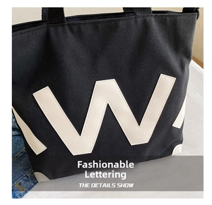 Gros plan détaillé d'un sac cabas en toile noire avec la lettre W blanche et texture du tissu
