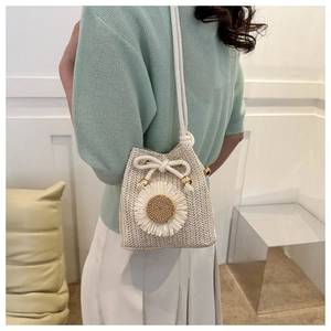 Detail of hand-woven straw bucket bag with floral accent and cotton drawstring strap
