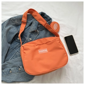 Détail du sac à bandoulière en nylon orange avec écusson et petit porte-monnaie rond