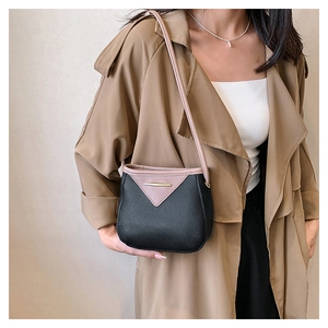 Close-up of contrast color bucket bag with black lychee leather and pink flap on model