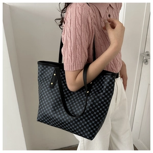 Detail of a large black tote bag with blue geometric patterns and gold rivet straps