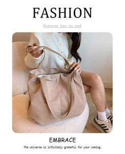 Close-up of a beige large-capacity nylon tote bag with leather logo detail and dual handles