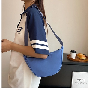 Blue nylon hobo bag shown on a model featuring a crescent shape and fabric strap