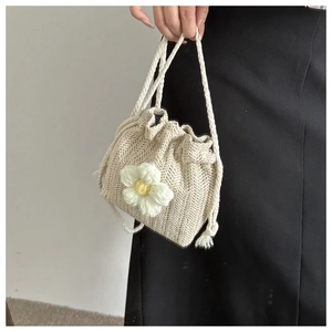 Detail of beige woven bucket bag with herringbone texture and crochet daisy flower