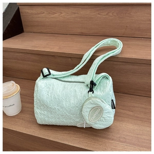 Detail of mint green quilted cylinder bag with small coin purse on wooden stairs