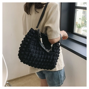 Detail of black bubble texture tote bag featuring pearl chain and leather shoulder strap