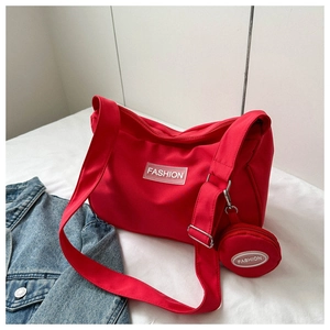 Vue détaillée du sac fourre-tout en nylon rouge avec logo sur un lit blanc épuré