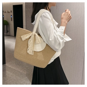 Detail of hand-woven straw tote bag with white lace bow and round patch decoration