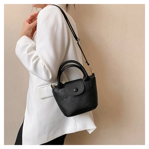 Detail of black lychee grain leather mini bag with gold hardware and top handle