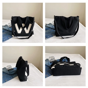 Détail de sac cabas en toile noire avec logo W blanc et bandoulière réglable