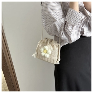 Detailed close-up of a hand-crocheted beige bucket bag with a 3D floral decoration