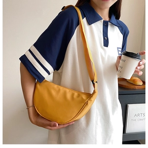 Close-up of lightweight yellow nylon crescent bag with adjustable strap in daily lifestyle use