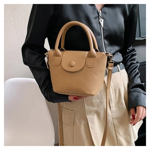 Close-up of khaki pebbled leather bucket bag with top handle and round buckle detail