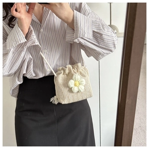 On-body view of a handmade cream crochet bucket bag featuring a large white flower detail