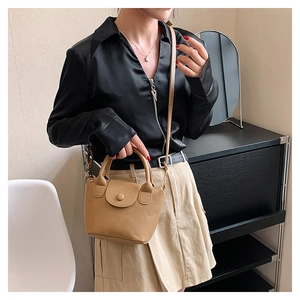 Detailed close-up of khaki pebbled leather bucket bag on model for daily commute