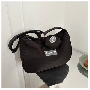 Détail du sac croissant en toile noire avec large bandoulière et petit porte-monnaie